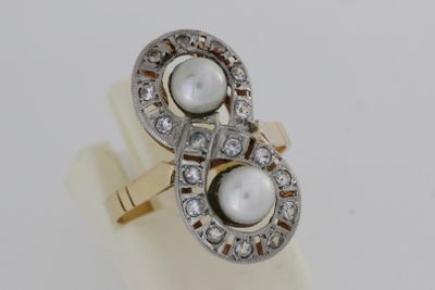 une photo d'une bague en perle blanche et diamants posée sur une surface blanche