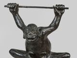 bronze sculpture of a monkey holding a bar on its back
