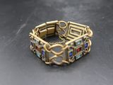 un gros plan sur un bracelet en or orné de pierres multicolores