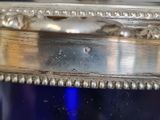 a blue glass container with a silver lid on a table