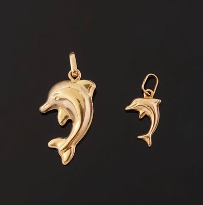 a pair of gold dolphin pendants on a black background