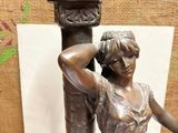 a statue of a woman holding a bird on top of a pillar