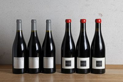 six bouteilles de vin rouge alignées sur une table en bois