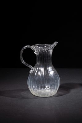 a glass pitcher sitting on a table with a black background