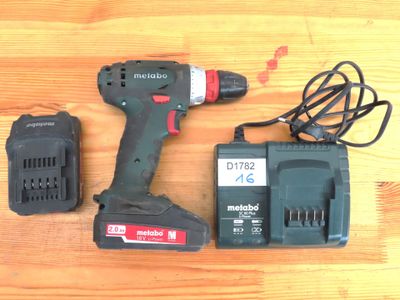 une perceuse filaire et deux batteries posées sur une table en bois