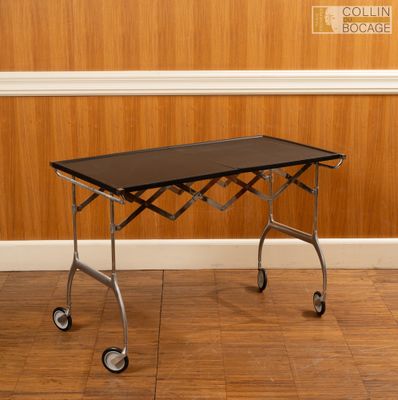 une photo d'une table noire à roulettes posée sur un parquet