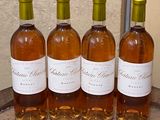 four bottles of wine are lined up on a wooden barrel
