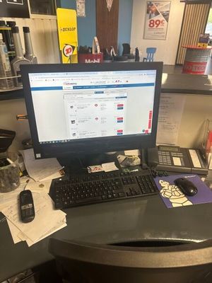 un bureau sur lequel se trouvent un ordinateur, un clavier, un téléphone et d'autres objets