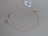 un collier avec une chaîne en or posé sur une table blanche