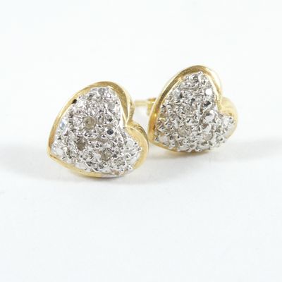 une paire de boucles d'oreilles en or et diamants en forme de cœur sur fond blanc