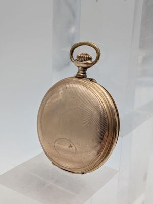 a gold pocket watch on display on a clear stand