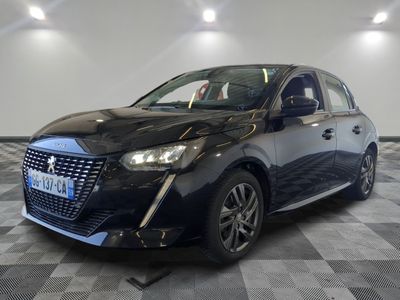 La voiture noire est garée dans une grande pièce au sol carrelé en damier.