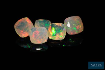 un gros plan sur un ensemble de pierres oplites posées sur une surface noire