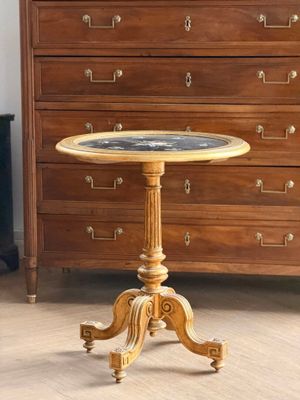 une petite table ronde avec un plateau en marbre posé sur un piètement en bois