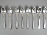 six silver spoons are lined up in a row on a table
