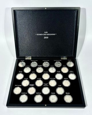 a black box with twelve silver coins in it on a white surface