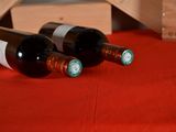 two bottles of wine sitting on a red table cloth