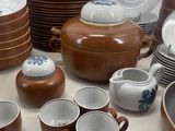 a lot of brown and white dishes and cups on the table