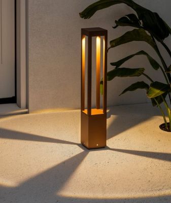 une photo d'une lampe posée par terre à côté d'une plante en pot