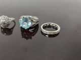 two rings and a ring with a blue topaz stone on a black surface