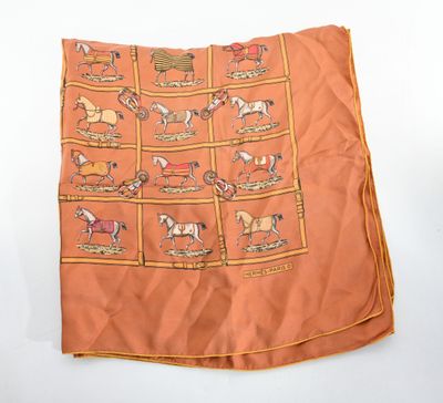 une écharpe orange avec des chevaux dessinés sur fond blanc