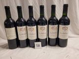 six bottles of red wine are lined up on a table