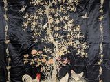 une image représentant une tenture murale brodée en noir et or, ornée d'oiseaux, de fleurs et d'un arbre