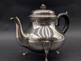 une théière ancienne en argent avec son couvercle, sur fond noir