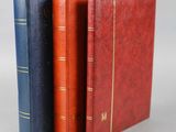 trois livres sont alignés les uns à côté des autres sur une surface grise