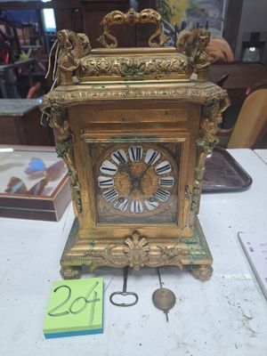 une horloge en or posée sur une table, avec une étiquette indiquant son prix
