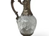 an antique silver and glass pitcher on a stand on a white background