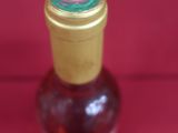 a small bottle of syrup on a red surface