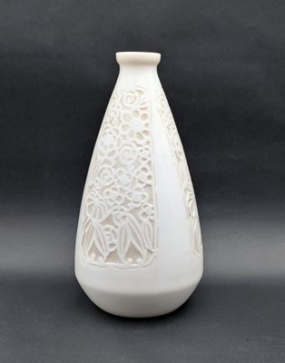 un vase blanc orné d'un motif sur fond noir