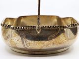 a silver bowl with a spoon in it on a white surface