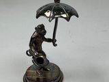a statue of a monkey holding an umbrella on a table
