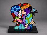 the figurine of a couple kissing each other on a black base