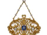 a close up of a necklace with a blue stone and pearls