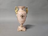 a pink vase with gold decoration on it on a stand