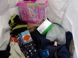 a basket full of clothes and toys on a bed