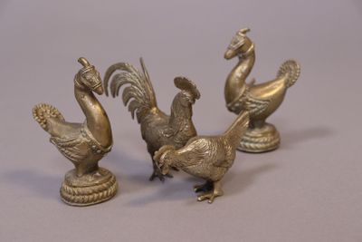 three brass figurines of birds on a table