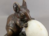 a statue of a mouse with an egg in it ' s mouth