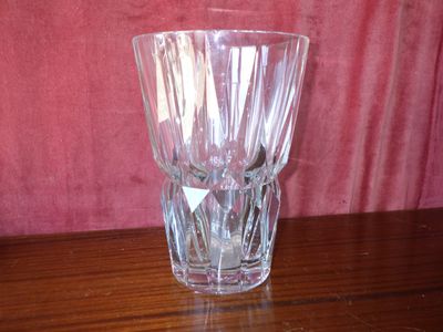 a glass vase sitting on a table with a pink wall behind it