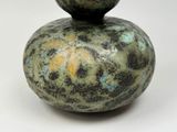 a green and blue vase sitting on top of a white table