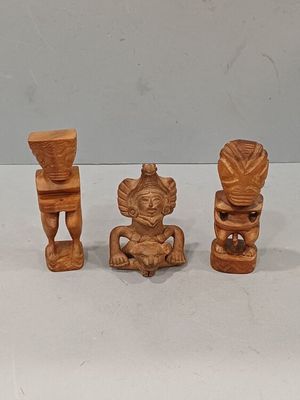 trois figurines en bois sculptées posées sur une surface blanche