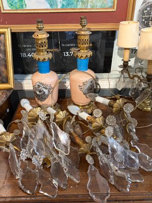 de nombreux vases en verre posés sur une table, avec un tableau en arrière-plan