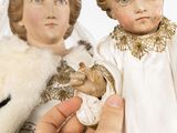 a person holding a doll with a doll in it ' s hand