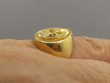 someone is holding a gold signet ring in their hand