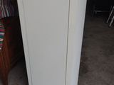 a white refrigerator sitting in a room next to a bed