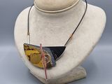 leather necklace with gold and black triangle pendant on a mannequin head