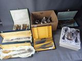 many different types of silverware in boxes on a table